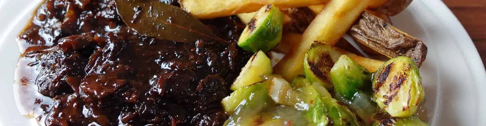 Runderschenkel in trappistenbier op zijn Vlaams met frieten, spruitjes en uienconfijt