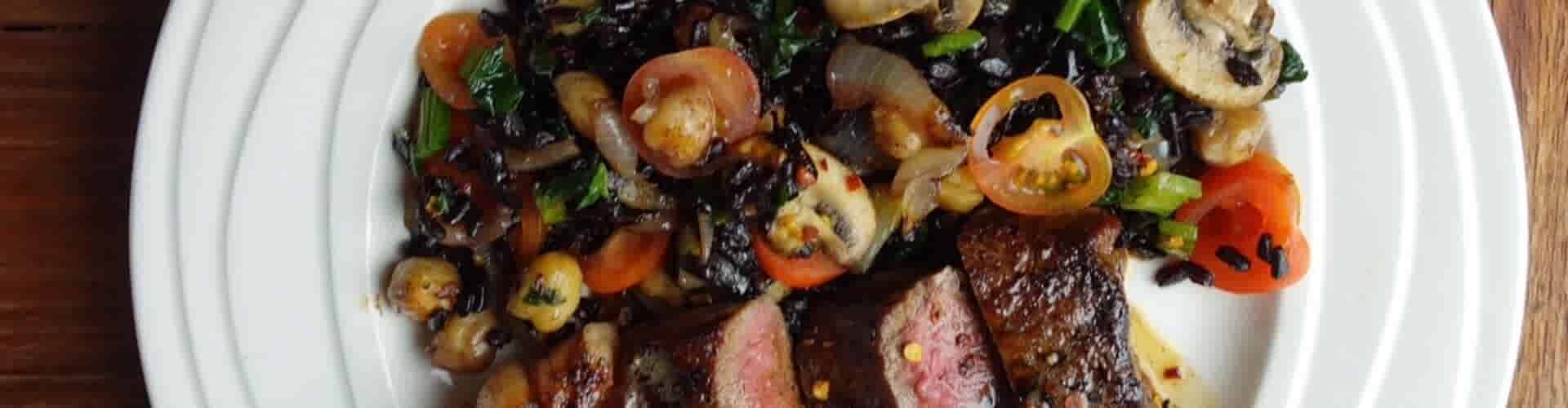 Grasgevoerde entrecote met zwarte rijst, kikkererwten, paddenstoelen en spinazie